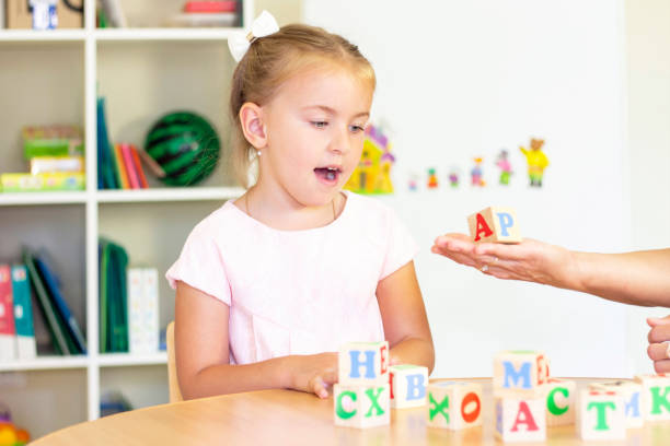 istock developmental and speech therapy classes with a child-girl. Speech therapy exercises and games with letters. dice game 1389438598