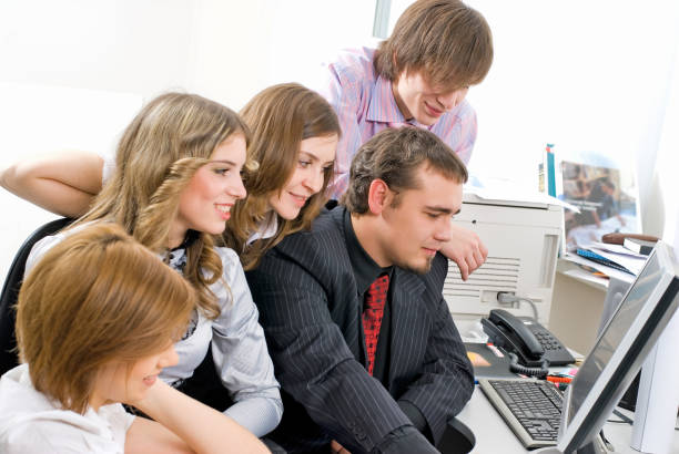 Brainstorm. Group of cheerful business people in smart casual wear looking at the laptop together and smiling