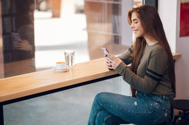 istock Woman using smartphone and drinking coffee in a cafe. 1389438735