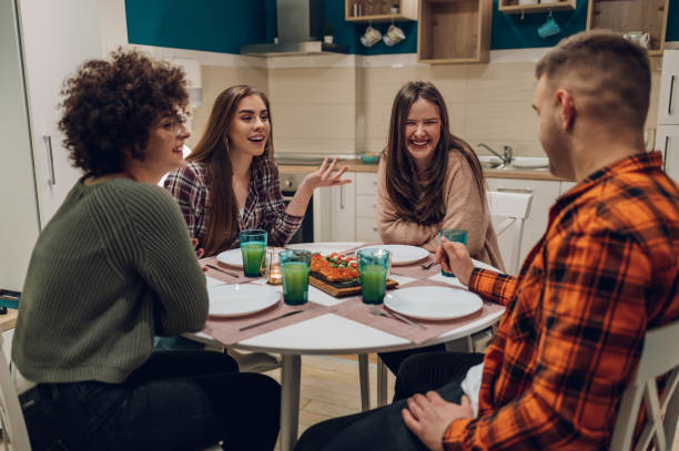 istock Group of friends enjoying dinner while sitting at the kitchen table together 1389438790