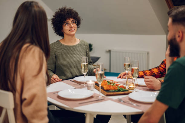 istock Group of friends enjoying dinner while sitting at the kitchen table together 1389438792