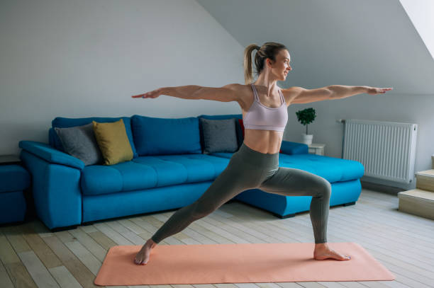 istock Woman training yoga at home an standing in Warrior Two pose. 1389438804