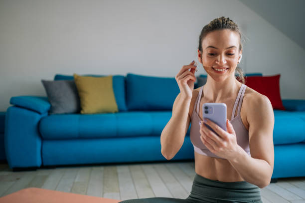 istock Woman using airpods and a smartphone while training at home 1389438811