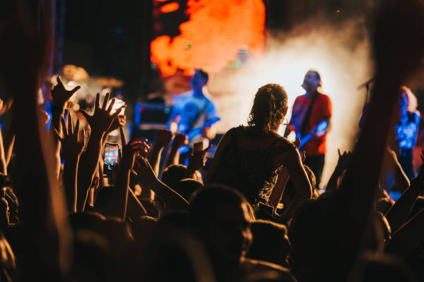 Silhouette of a woman with raised hands on a concert Silhouette of a woman with raised hands enjoying the concert. Youth and celebration concept. performance group stock pictures, royalty-free photos & images