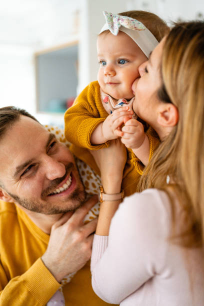 Proud mother and father smiling at their baby daughter at home stock photo