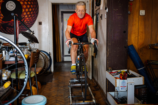 old man Athlete cycling at home, sportsperson training with road bicycle at home