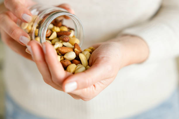Nuts spilling from jar in woman's hand stock photo
