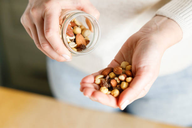 istock Nuts spilling from jar in woman's hand 1389442791
