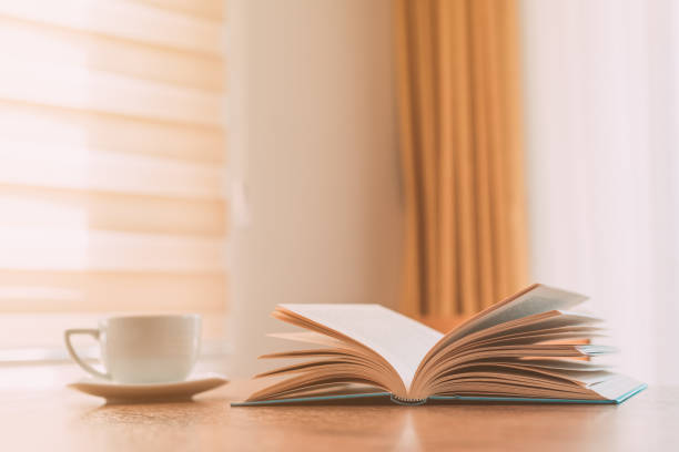 istock Open book and coffee cup on the table, reading at home in the morning 1389446558