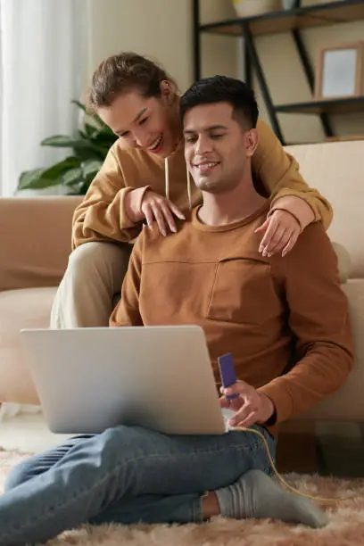 Happy young couple paying for streaming service subscription to watch new episode of favorite show