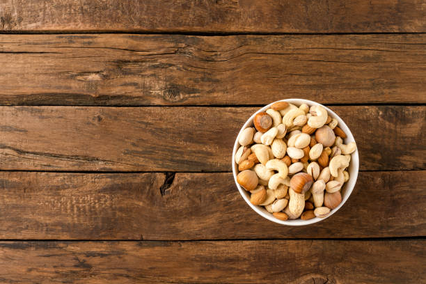 istock Various kinds of nuts (almonds, pistachios, peanuts, hazelnuts and cashews) in bowl on wooden table. Close up 1389449404