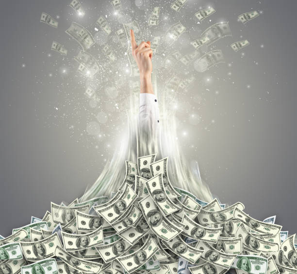 istock Hand bursting out from a money heap 1389450594