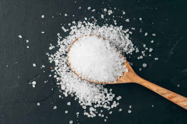 istock Sea salt on wooden spoon on black background 1389453718