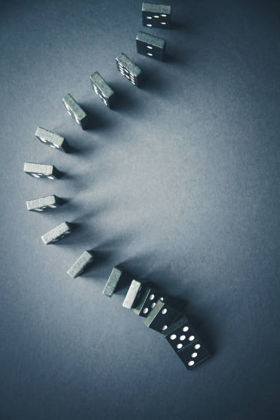 Black dominoes chain on dark table background Black dominoes chain on a dark table background. Domino effect concept domino effect stock pictures, royalty-free photos & images