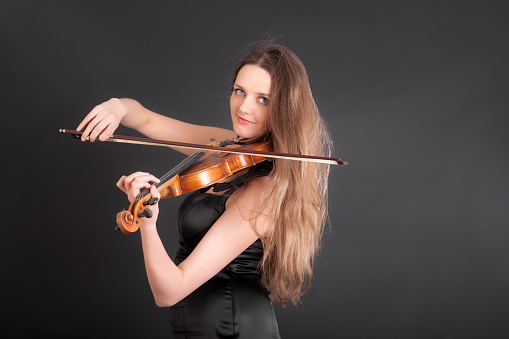 studio portrait of a violinist with long hair on a black background