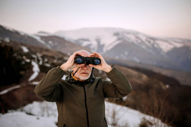 istock Senior man using binoculars on the top of the mountain 1389457418