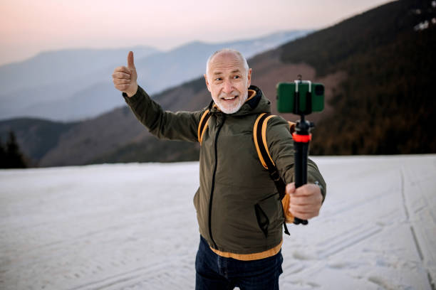vlogger de viajes senior grabándose a sí mismo en la cima de la montaña - only men senior men snow tripod fotografías e imágenes de stock