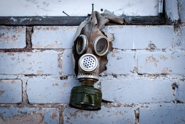 Old gas mask with coal filter hung on the brick wall. Concept - Nuclear Disarmament and Radiation Protection, epidemic, coronavirus, covid-19, pandemic.