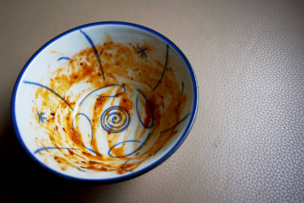 Two empty bowls with spoons on a wooden table after a meal.