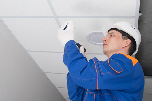 Closeup side view of a middle aged construction worker applying plaster onto a ceiling.