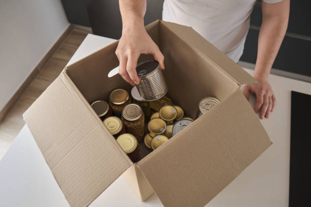 istock Unrecognizable man filling donation box with non-perishable food. 1389459336