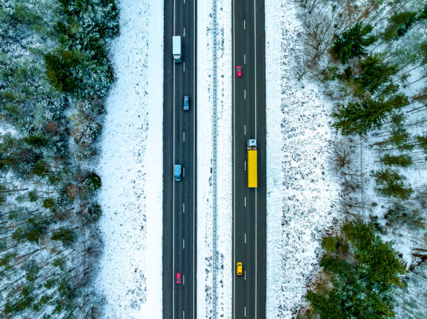 autopista a través de un paisaje de bosque nevado visto desde arriba - highway traffic aerial view netherlands fotografías e imágenes de stock