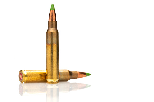 A pair of 5.56 calibar, green tip bullets on white background