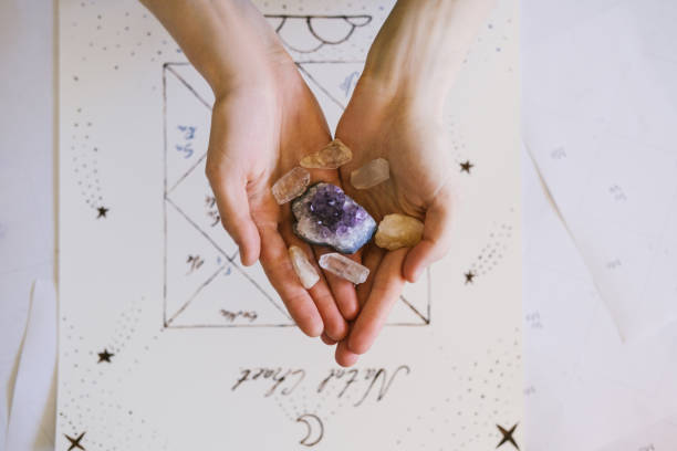 istock Woman holding crystals in her hands. Natal chart and background. 1389463269