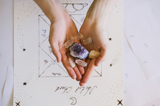 woman holding crystals in her hands. Natal chart and astrology background.