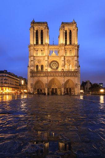 Beautiful cityscape view of the Notre-Dame Cathedral in Paris, France, on a rainy spring evening with reflection in the blue hour