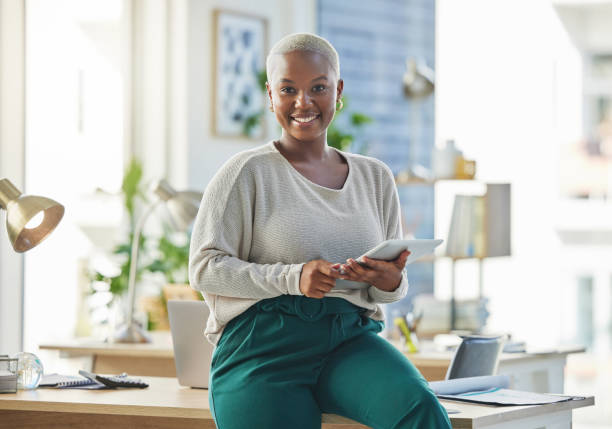 shot of a young businesswoman using a digital tablet in her office - businesswoman business women african descent imagens e fotografias de stock