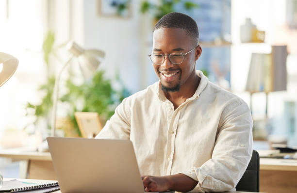 zdjęcie młodego biznesmena pracującego na laptopie przy biurku - african descent zdjęcia i obrazy z banku zdjęć