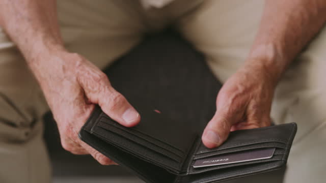4k video footage of a senior man looking at an empty wallet at home