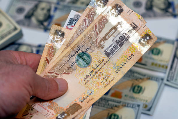 istock man hand holding a stack of United Arab Emirates 200 two hundred dirhams money, spending, giving and using money concept, paying and buying 1389468747