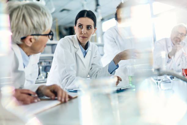 istock Group of chemists communicating while working in laboratory. 1389472068
