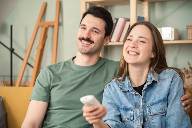 istock Happy couple watching TV at home 1389474330