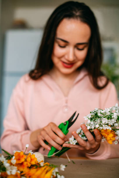 istock Young Woman Arranging Spring Flowers 1389474366