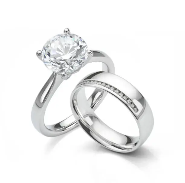 Solitaire diamond engagement ring with diamond wedding ring on white background.