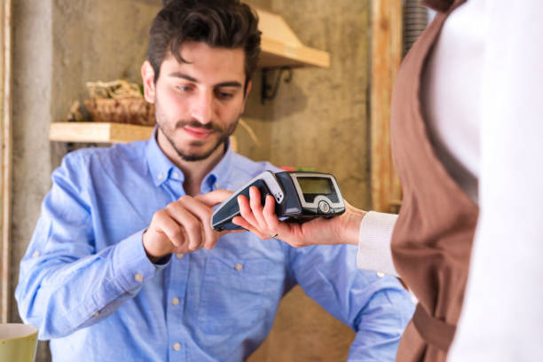 istock Young man paying with contactless credit card at cafe 1389475771