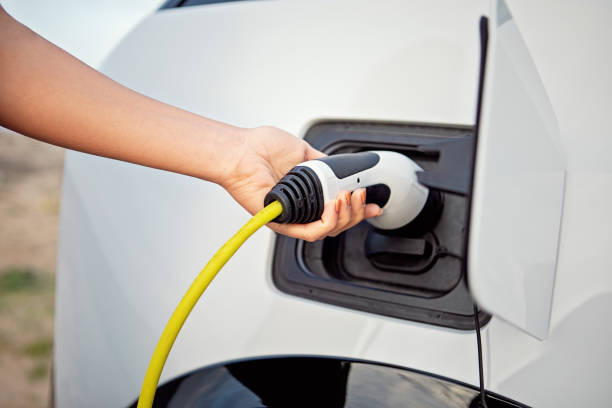 istock Woman is plugging/unplugging cable to electric car 1389478093