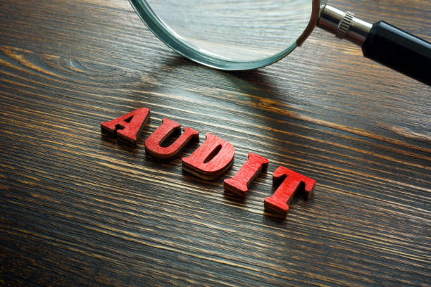istock Wooden letters audit and a magnifying glass. 1389478566
