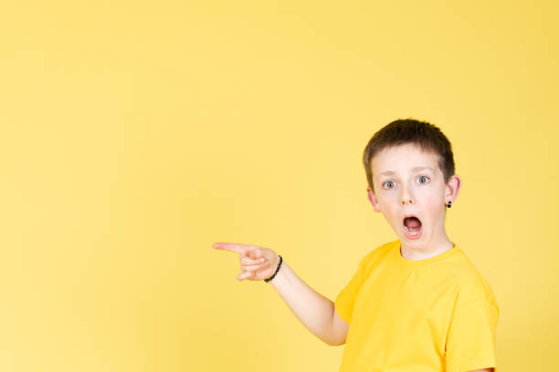 istock Surprised boy looking at camera and pointing to side 1389478669