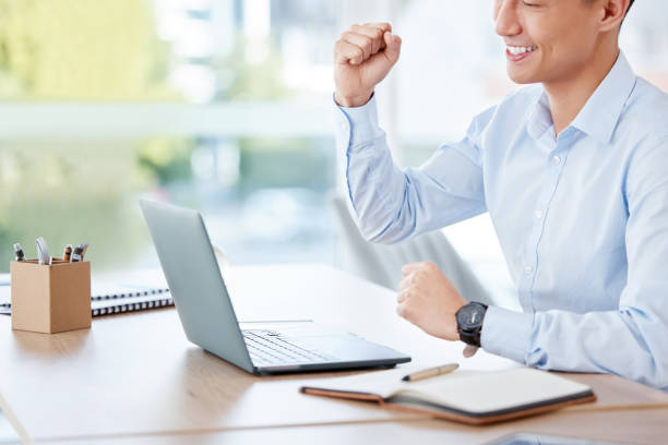 aufnahme eines jungen geschäftsmannes, der jubelt, während er bei der arbeit einen laptop benutzt - office chair cheering ecstatic success stock-fotos und bilder