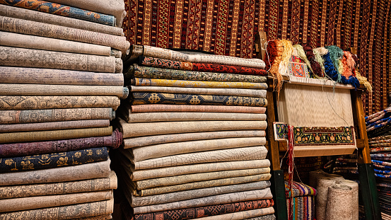 Stacks of Turkish carpets next to a loom in the basement of a shop in Istanbul, Turkey.