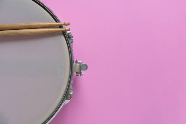 istock Drum stick and drum on pink table background, top view, music concept 1389479462