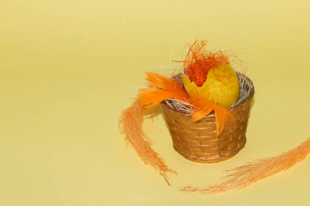 yellow egg shell with decorative orange straw in a vintage basket, creative vintage wallpaper with copy space, happy easter