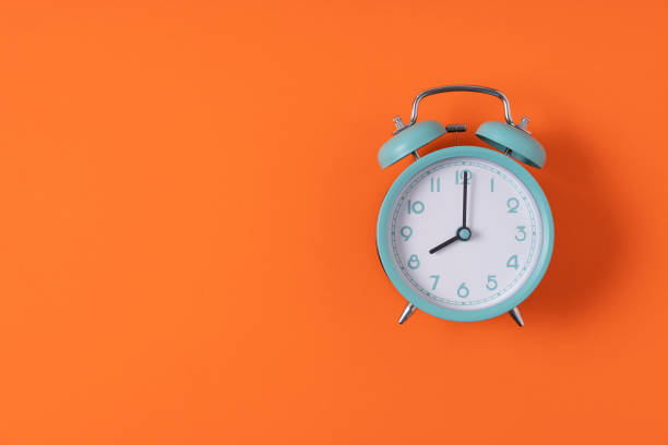 istock Retro alarm clock on orange table background, vintage style, flat lay 1389479823