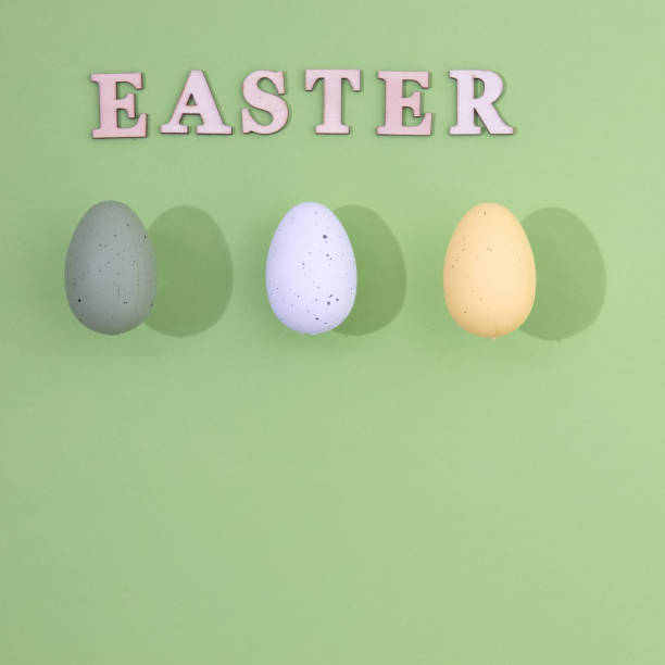 istock Three Easter eggs of different colors with a stronger shade and the inscription Easter made of wood on a light green background with copy space. Minimal holiday composition. 1389480933