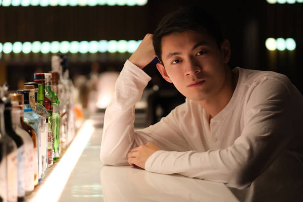 istock handsome Asian young man sitting at bar counter, looking at camera 1389482442