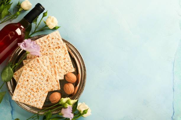 Passover celebration concept. Matzah, red kosher walnut and spring beautiful rose flowers. Traditional ritual Jewish bread on light turquoise or blue background. Passover food. Pesach Jewish holiday. Passover celebration concept. Matzah, red kosher walnut and spring beautiful rose flowers. Traditional ritual Jewish bread on light turquoise or blue background. Passover food. Pesach Jewish holiday. matzo stock pictures, royalty-free photos & images